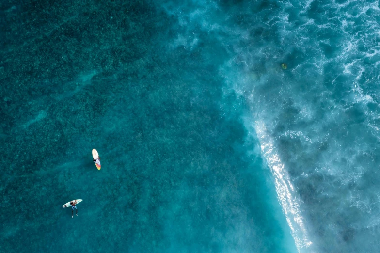 a couple of people riding surfboards on top of a body of water, by Peter Churcher, pexels contest winner, birds eye, reefs, teal aesthetic, thumbnail