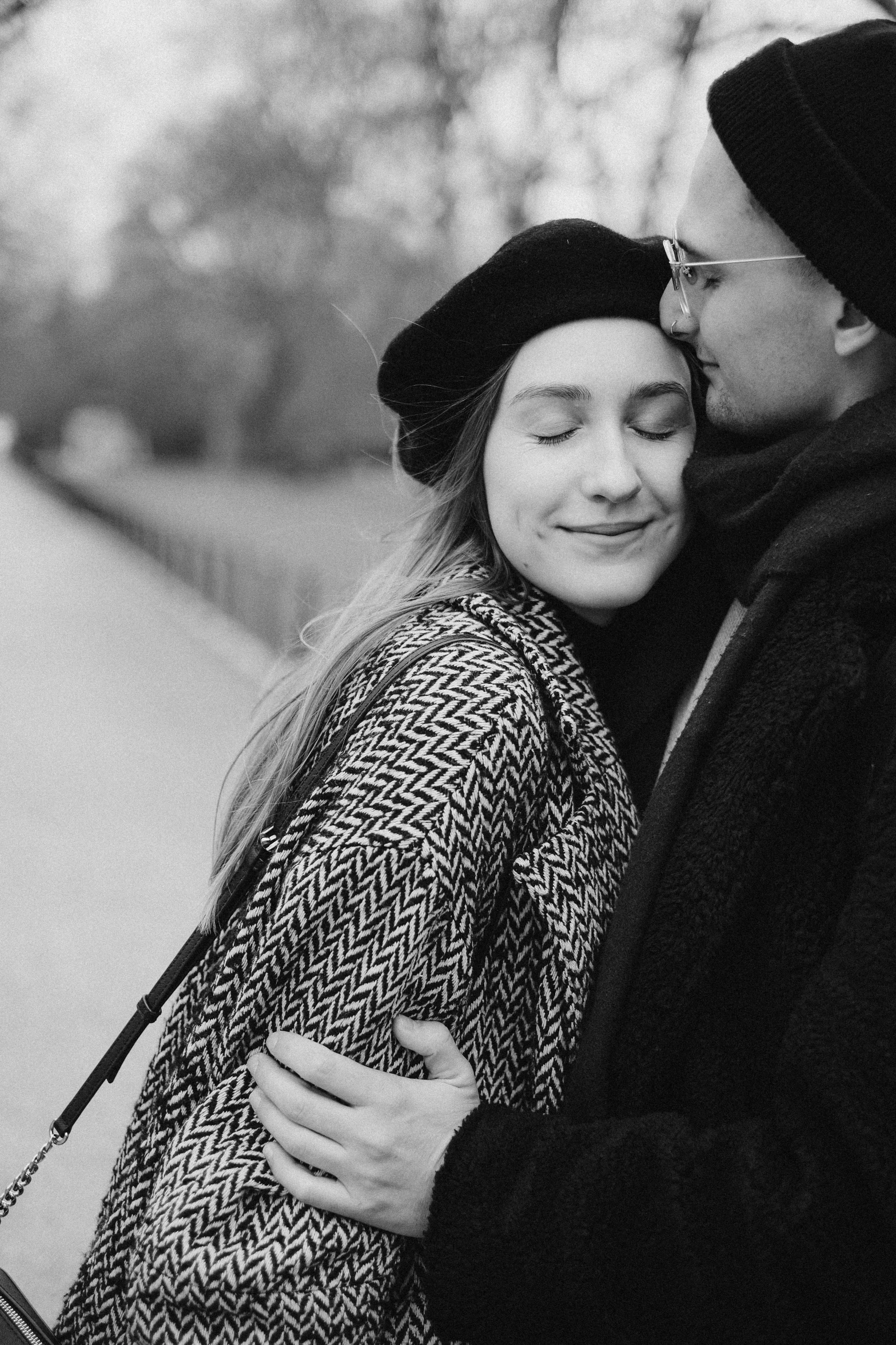 a man and a woman standing next to each other, a black and white photo, pexels contest winner, cuddling, wearing a beret, gif, girl wearing hoodie