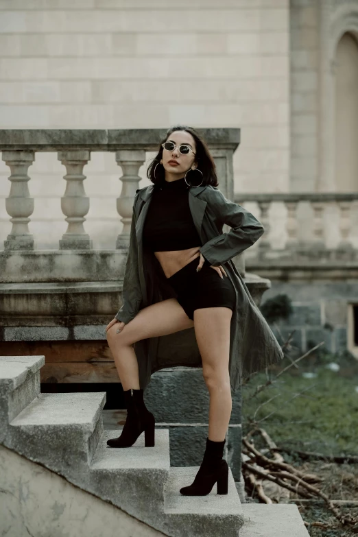 a woman standing on the steps of a building, trending on pexels, baroque, wearing leather swim suite, short coat, bella poarch, doing a sassy pose