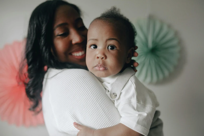 a woman holding a baby in her arms, a picture, by Arabella Rankin, pexels contest winner, mixed race, thumbnail, high quality image, rectangle