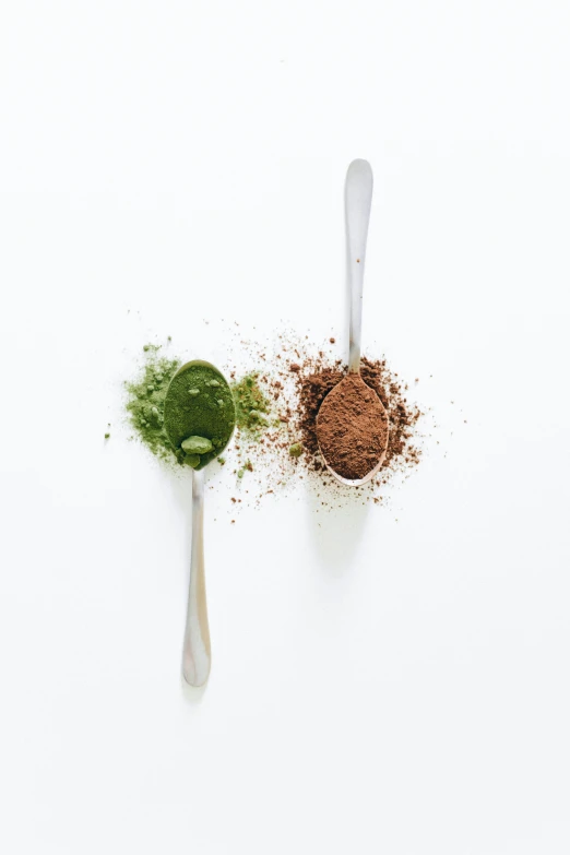 a couple of spoons sitting next to each other, green and brown color palette, powder, product image, full product shot