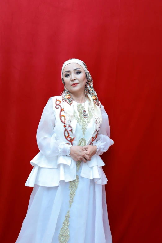 a woman in a white dress standing in front of a red backdrop, inspired by Nazmi Ziya Güran, hurufiyya, wearing authentic attire, vocalist, ((portrait)), white backround