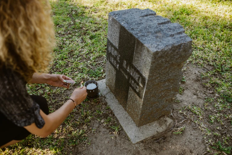 a woman that is kneeling down next to a grave, unsplash, visual art, drink, sydney hanson, local close up, cast