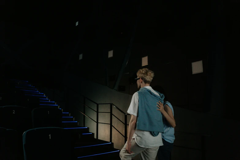 a couple of people that are standing in the dark, unsplash contest winner, light and space, theater, cai xukun, her back is to us, penrose stairs