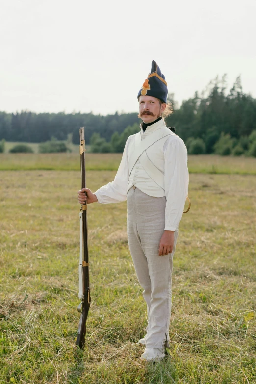 a man standing in a field holding a stick, an album cover, by Attila Meszlenyi, historical reenactment, wear an elegant mustach, finland, still from a wes anderson movie