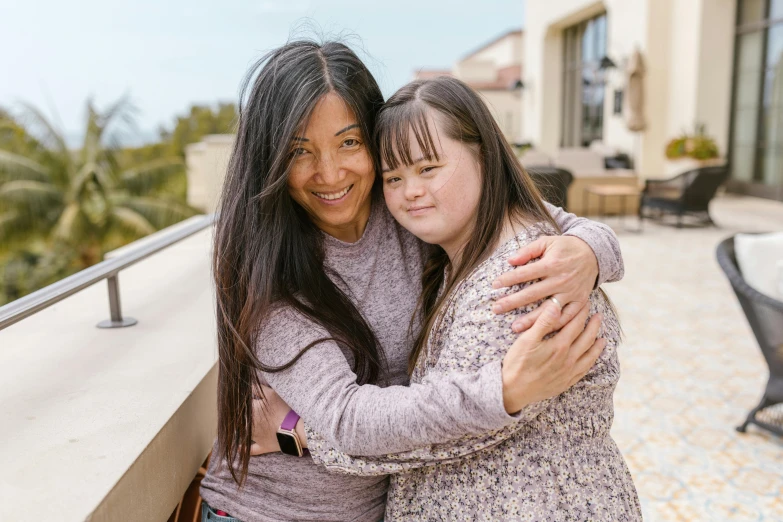 two women hugging each other on a balcony, a picture, pexels contest winner, hurufiyya, andy milonakis, nanae kawahara, holding an epée, profile image