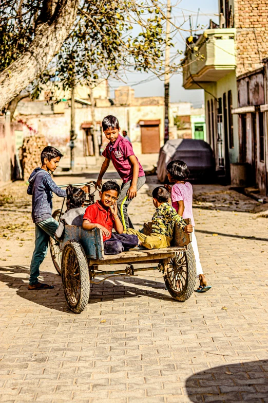 a group of people riding on the back of a horse drawn carriage, by Peter Churcher, pexels contest winner, happening, kids playing, in a village, square, on an indian street