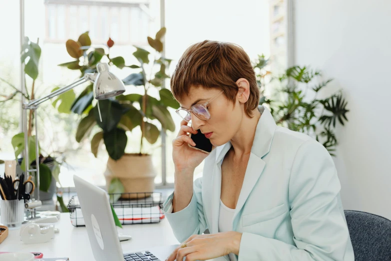 a woman sitting at a desk talking on a cell phone, trending on pexels, next to a plant, avatar image, office clothes, multicoloured