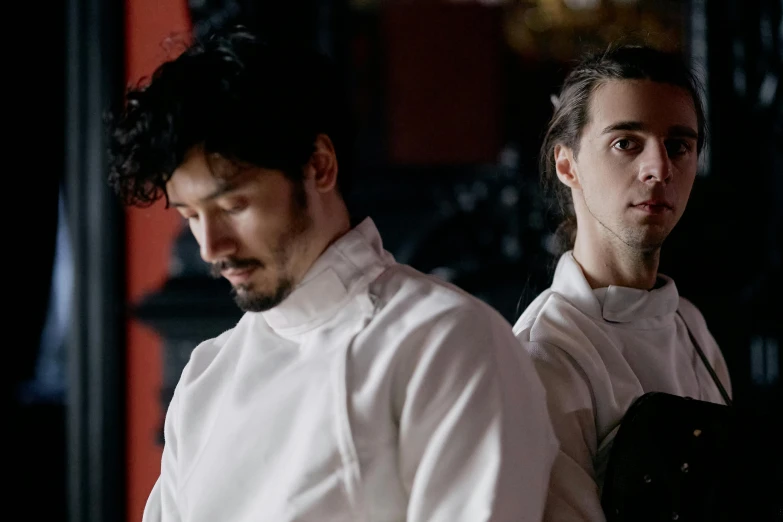 a couple of men standing next to each other, an album cover, inspired by Caravaggio, pexels contest winner, cuisine, still from a music video, mingchen shen, looking serious