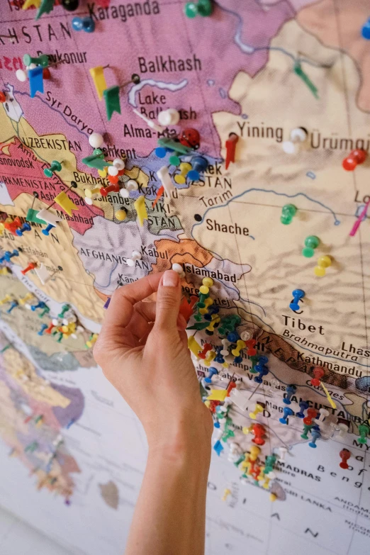 a person pointing at a map with pins on it, by Julia Pishtar, kurdistan, toys, detail shot, whiteboards