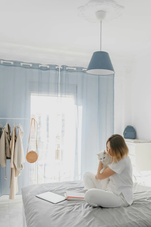 a woman sitting on a bed reading a book, pexels contest winner, light and space, pale blue outfit, 15081959 21121991 01012000 4k, tiles curtains, woman drinking coffee