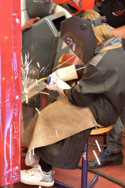 a group of people working on a piece of metal, wearing metal gauntlet, student, amateur photograph, sarah