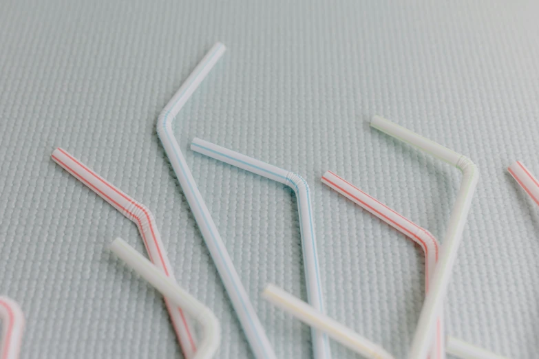 a bunch of straws sitting on top of a table, inspired by Cerith Wyn Evans, unsplash, minimalism, silicone cover, detail shot, curved, traditional medium