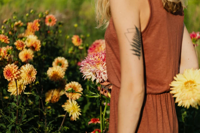 a woman standing in a field of flowers, a tattoo, dahlias, understated aesthetic, next to a plant, profile image