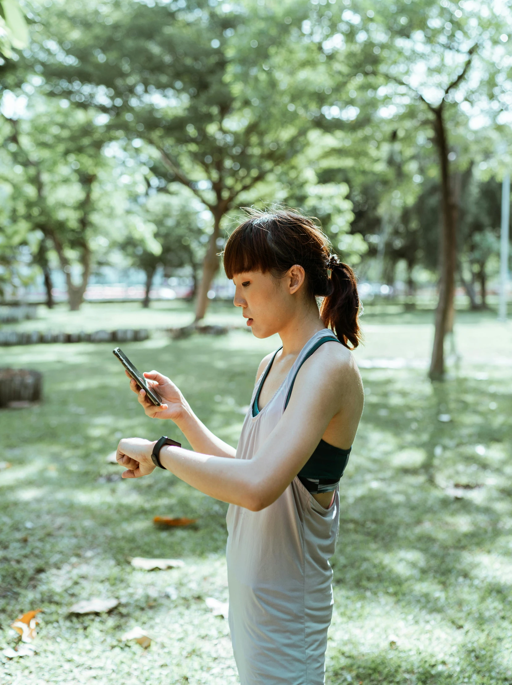 a woman standing in a park looking at her cell phone, pexels, happening, wearing fitness gear, of taiwanese girl with tattoos, square, movie photo