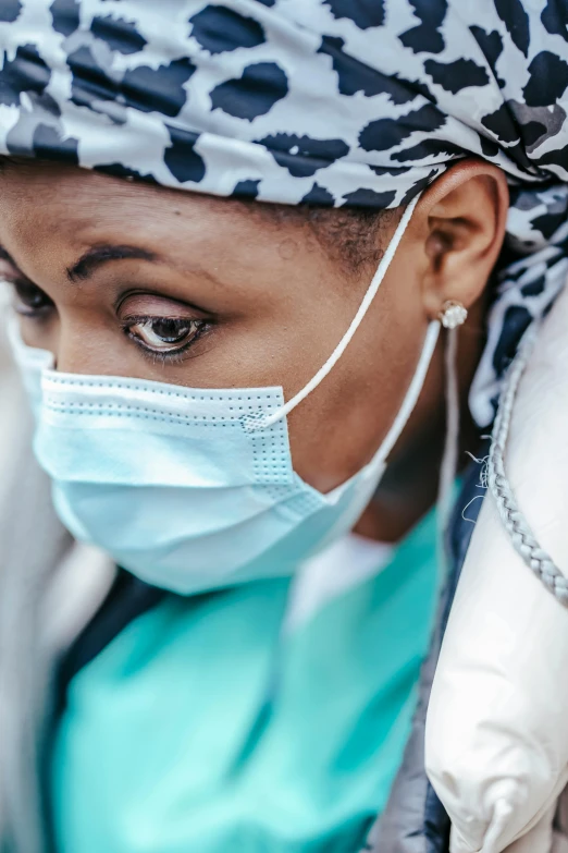 a close up of a person wearing a face mask, a picture, surgical gown and scrubs on, somali woman, gaze down, struggling