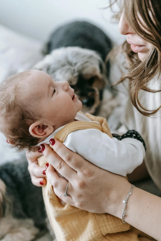 a woman holding a baby in her arms, pexels contest winner, holding paws, next gen, profile image, many small details