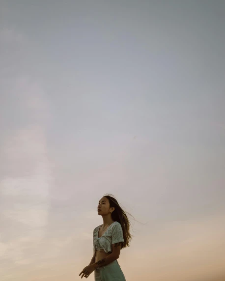 a woman standing on top of a beach next to the ocean, a picture, unsplash, happening, portrait soft low light, as she looks up at the ceiling, sky setting, low quality photo