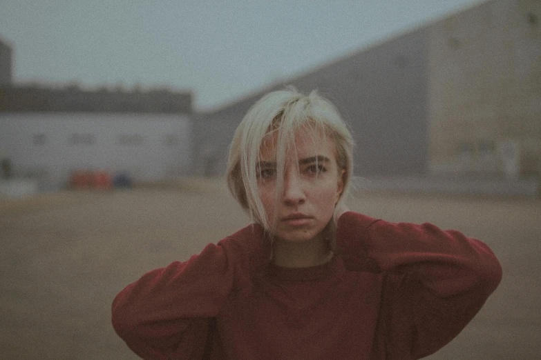 a woman with blonde hair standing in front of a building, inspired by Elsa Bleda, unsplash contest winner, photorealism, short platinum hair tomboy, portrait rugged girl, faded red and yelow, dua lipa