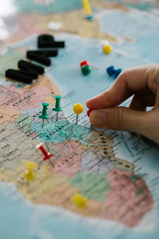 a close up of a person pointing at pins on a map, uploaded, top, travel, playing