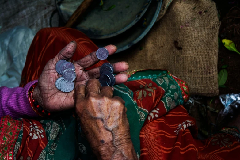 a close up of a person holding a coin, inspired by Steve McCurry, pexels contest winner, arte povera, old dhaka, witch paying for her sins, textiles, tins of food on the floor