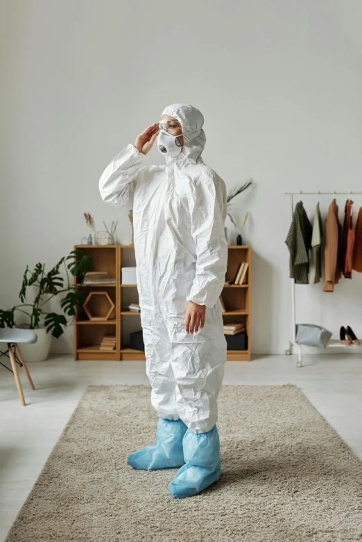 a man in a protective suit talking on a cell phone, an album cover, by Andries Stock, shutterstock, standing in corner of room, dress and cloth, sustainable materials, hazmat suits