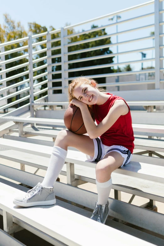 a girl sitting on a bleachers holding a basketball, wearing red shorts, wearing white sneakers, carson ellis, profile image