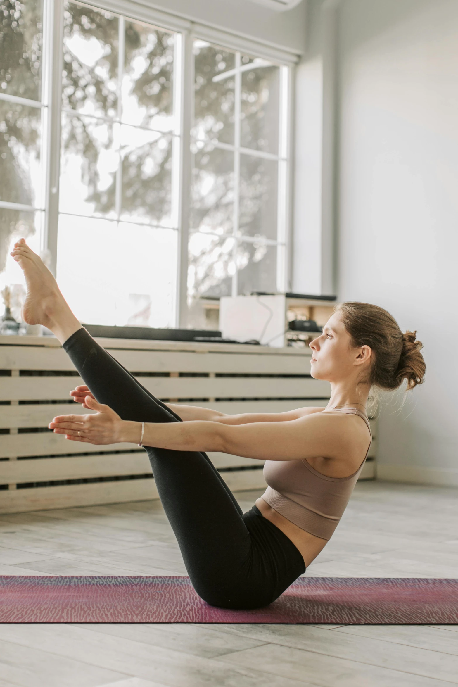 a woman doing a yoga pose in front of a window, pexels contest winner, arabesque, physical : tinyest midriff ever, square, boat, studio