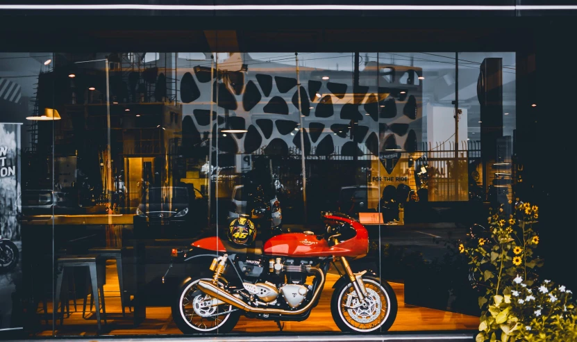 a red motorcycle parked in front of a building, by Tom Bonson, pexels contest winner, award winning shopfront design, golden windows, triumph, transparent black windshield