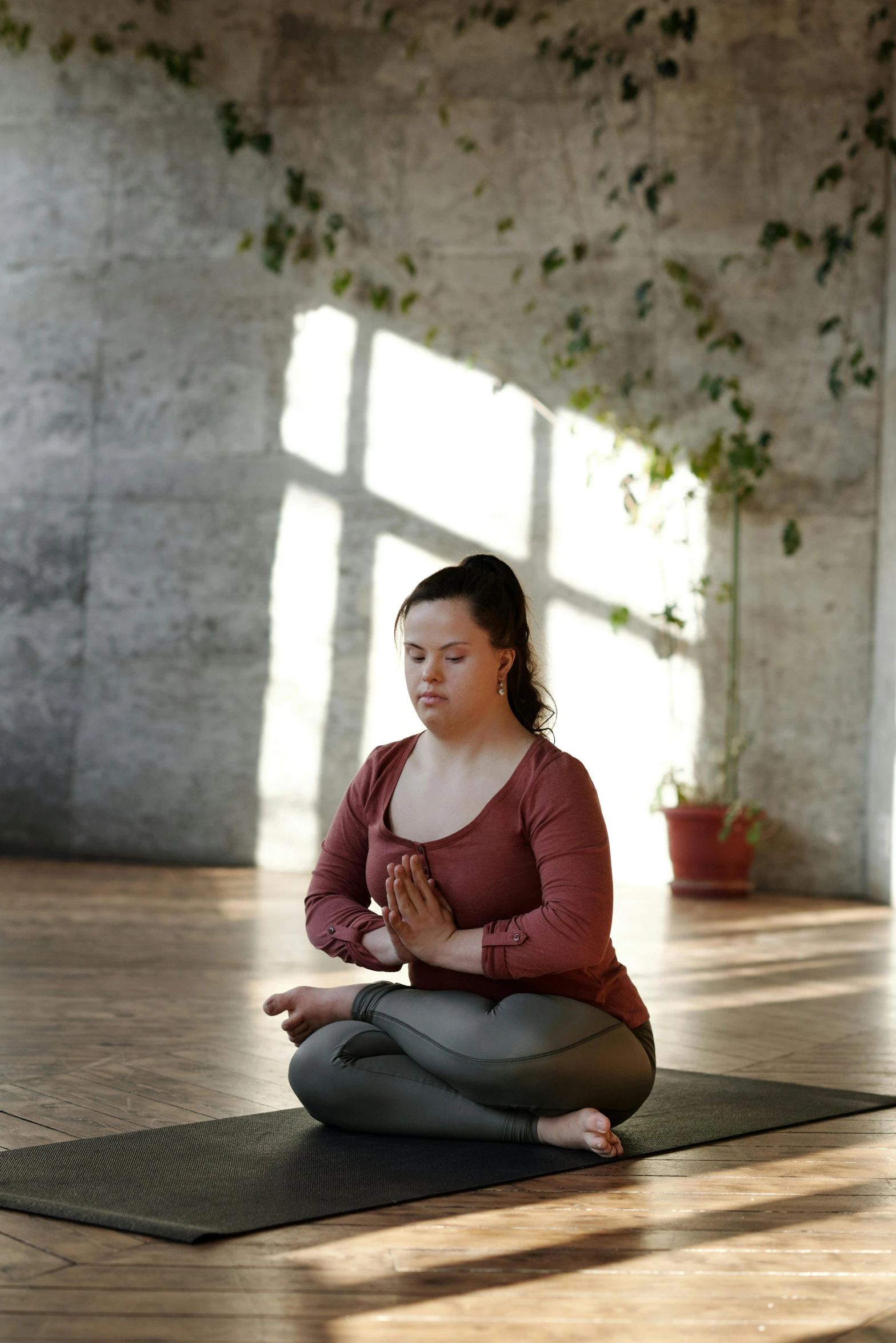 a woman sitting on a yoga mat in a room, pexels contest winner, renaissance, praying posture, low quality photo, sun light, promo image