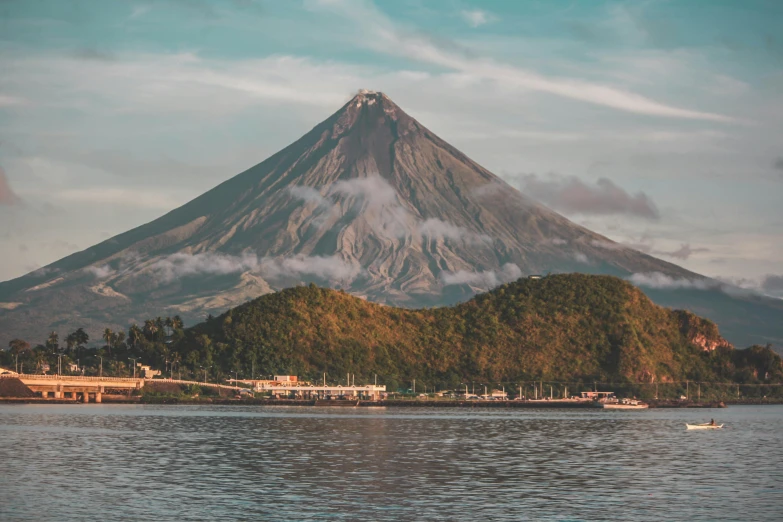 a large mountain towering over a body of water, by Julia Pishtar, pexels contest winner, sumatraism, 1970s philippines, volcano background, 🦩🪐🐞👩🏻🦳, pyroclastic flow