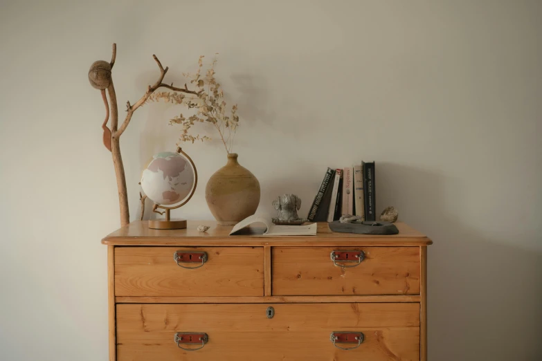 a wooden dresser with a vase on top of it, by Andries Stock, pexels contest winner, large globe, maritime pine, minimal artifacts, small library