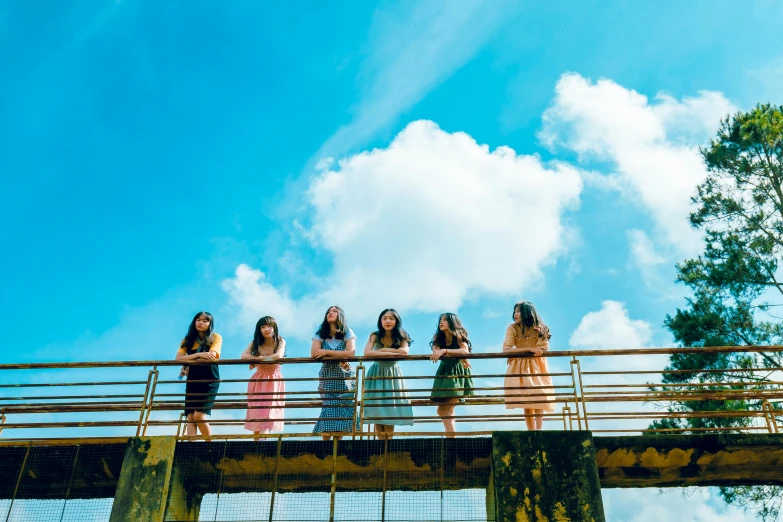 a group of women standing on top of a bridge, by Nathalie Rattner, pexels contest winner, clear blue sky vintage style, kpop, girl clouds, ren heng