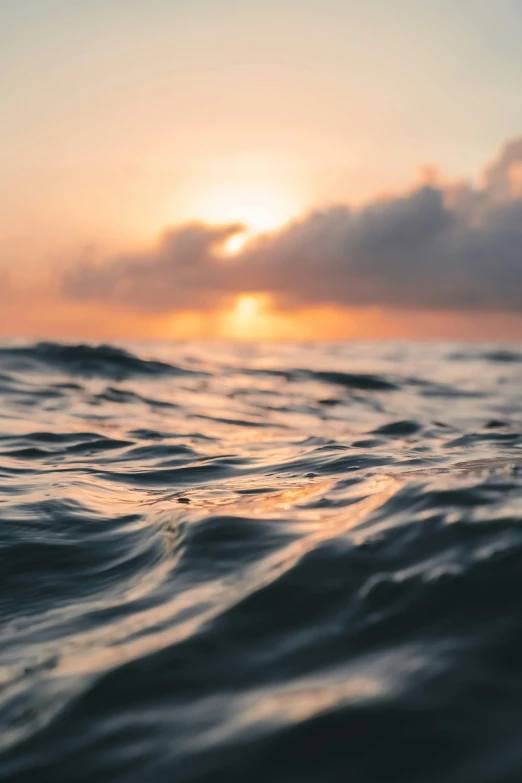 a close up of a body of water with a sunset in the background, wavy, in the ocean