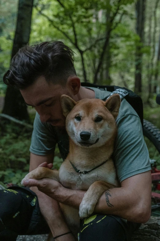 a man holding a dog in the woods, inspired by Shiba Kōkan, trending on unsplash, picture of a male biker, lil peep, ignant, tourist photo