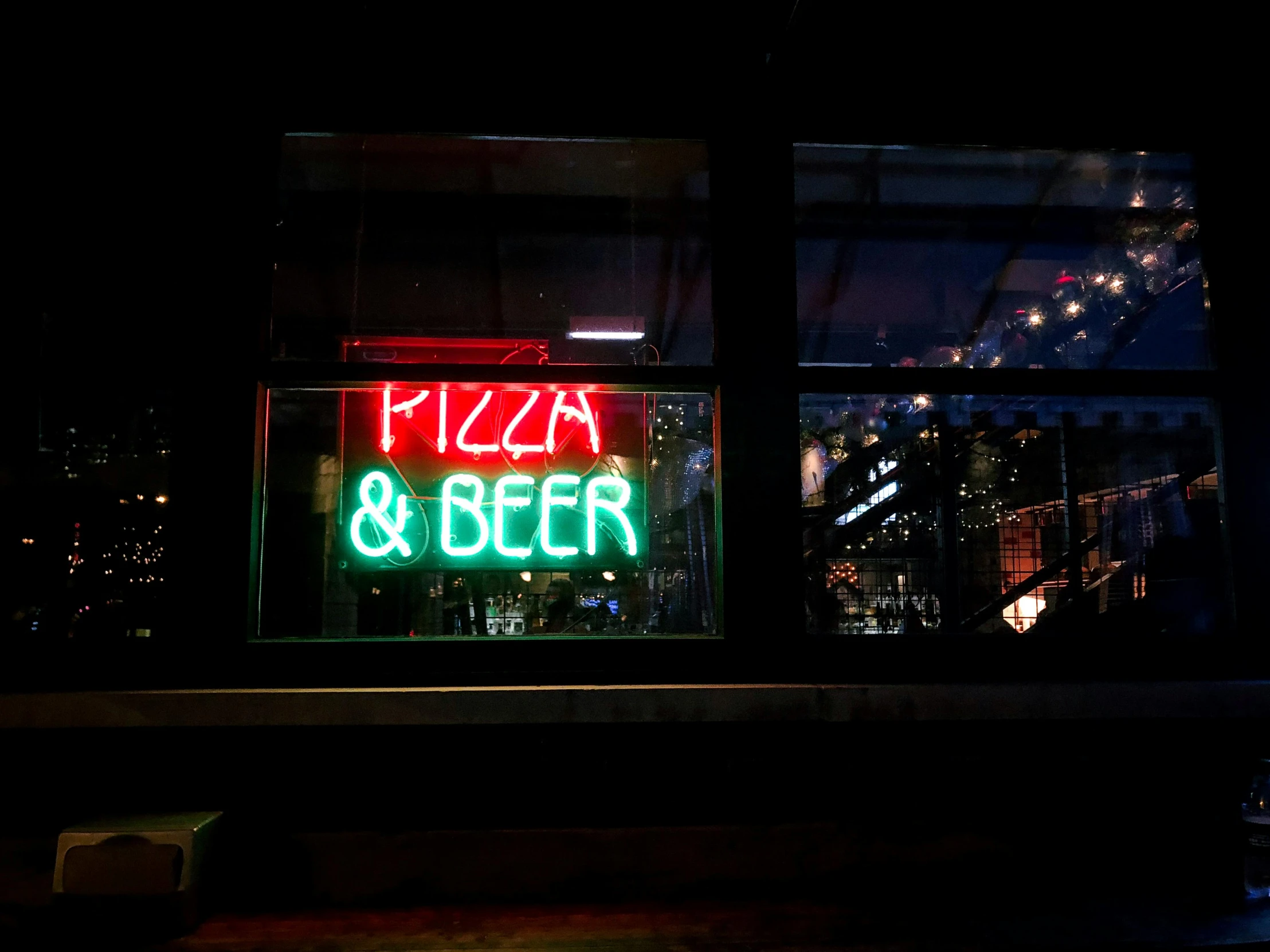 a neon sign in the window of a pizza and beer shop, by Meredith Dillman, pexels, pizza skyscrapers, pitch black room, peter guthrie, getty images