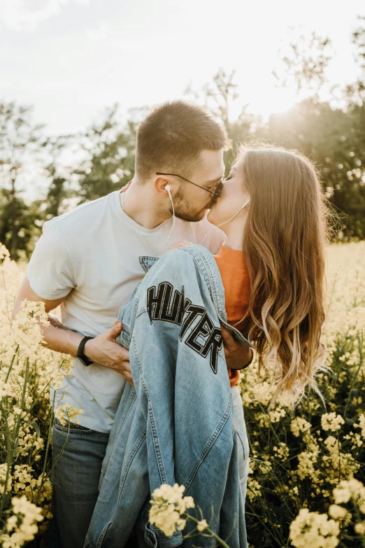 a man and woman kissing in a field of flowers, trending on pexels, wearing a jeans jackets, profile image, vine, girls