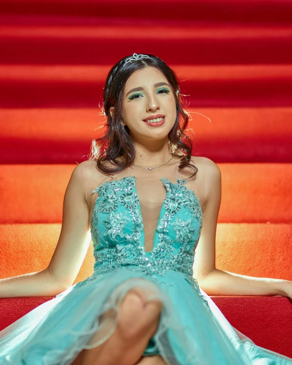 a woman in a blue dress sitting on a red staircase, an album cover, inspired by Julia Pishtar, trending on reddit, mahira khan as a d&d wizard, posing in leotard and tiara, mai anh tran, lgbtq