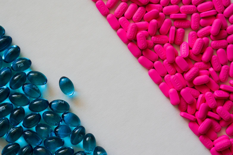 a white table topped with blue and pink pills, a picture, pexels, plasticien, teal and pink, image split in half, hot pink, 2 colours