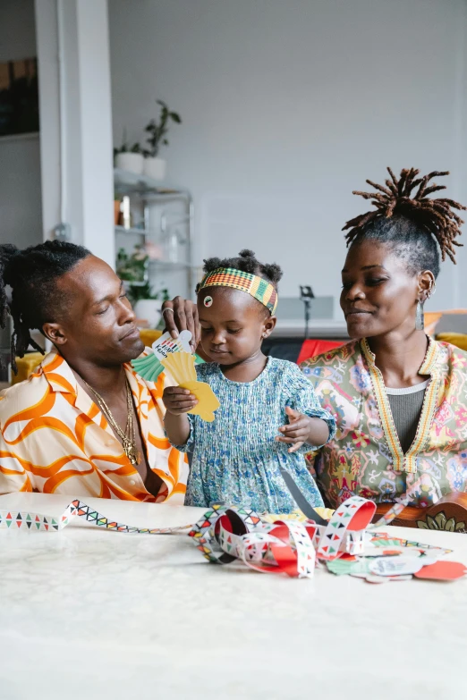 a group of people sitting around a table, by Ingrida Kadaka, pexels contest winner, black arts movement, portrait of family of three, wearing festive clothing, lgbtq, lupita nyong'o