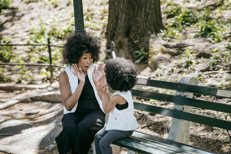 a woman and a child sitting on a bench, pexels contest winner, curly afro, emanating magic from her palms, naomi campbell, humans of new york