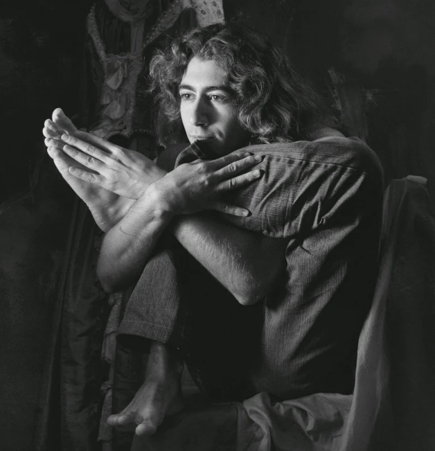 a black and white photo of a man sitting on a chair, anjali mudra, hozier, circa 1992, praying