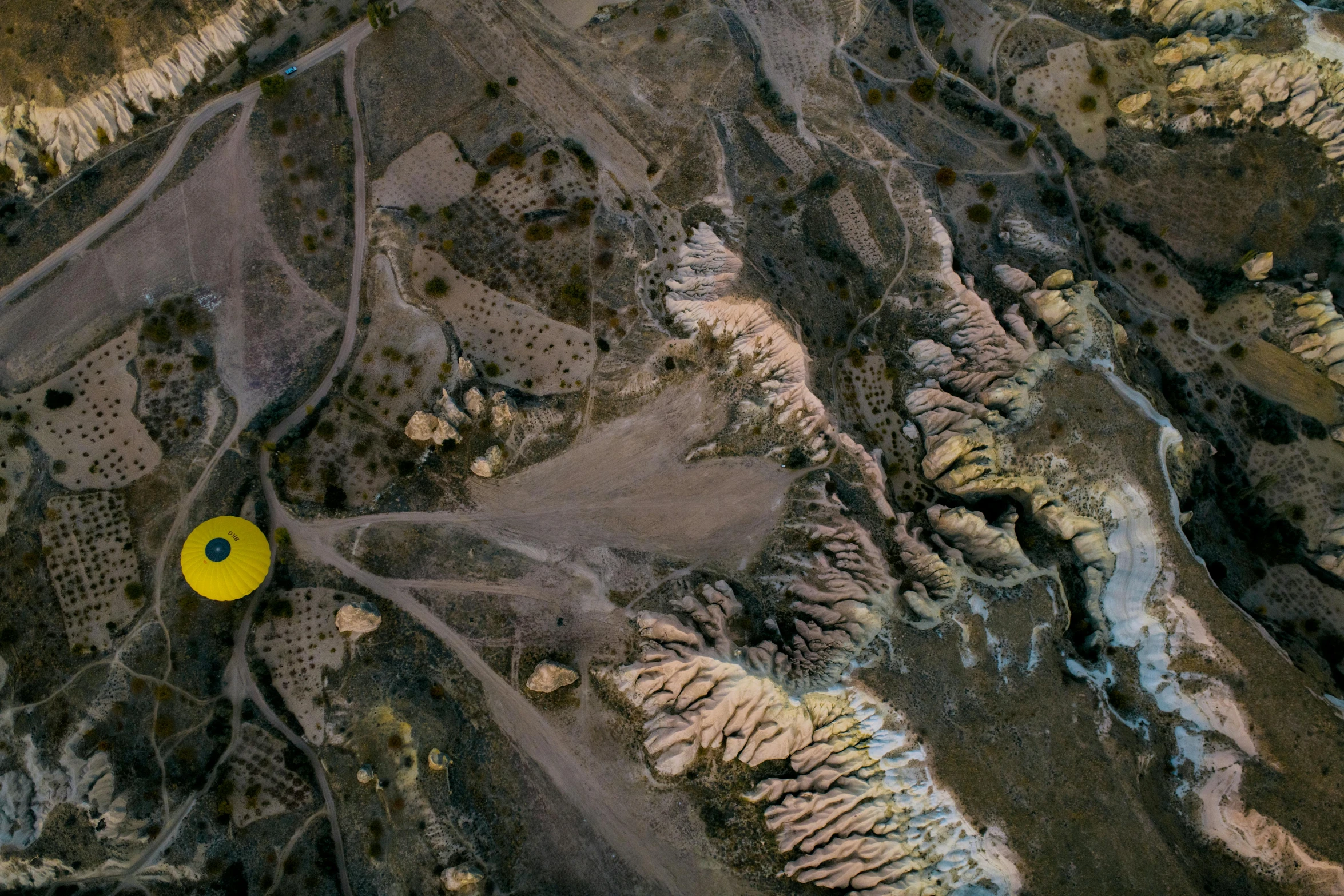 a yellow frisbee sitting on top of a dirt field, a cave painting, by Peter Churcher, pexels contest winner, land art, satellite view, balloon, shot on sony a 7 iii, contain