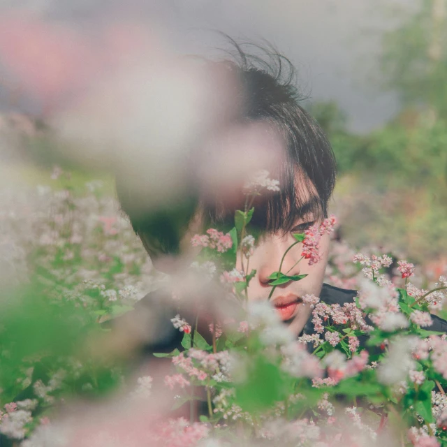a woman standing in a field of flowers, inspired by Elsa Bleda, pexels contest winner, asian man, hiding behind obstacles, with soft bushes, male ulzzang