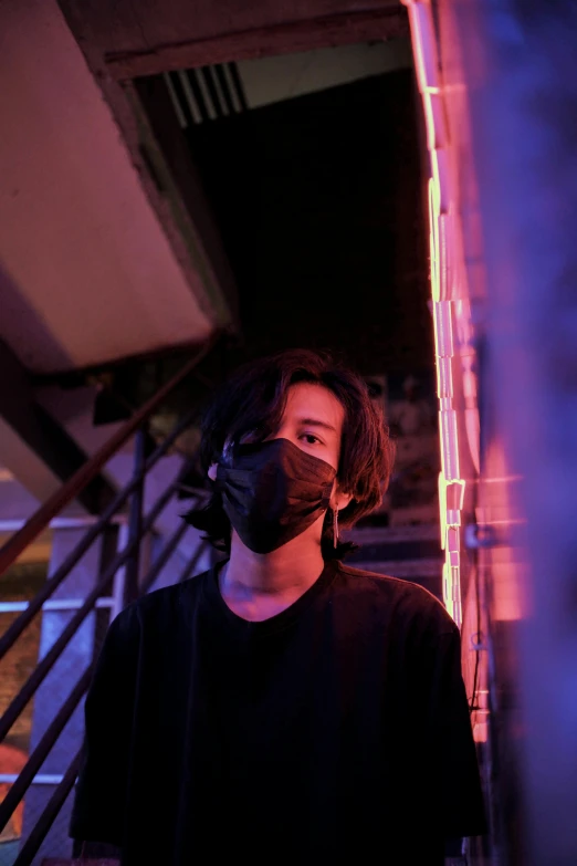 a man in a black shirt and a black mask, an album cover, inspired by Liam Wong, unsplash, looking away from camera, lights, small chin, indoor picture