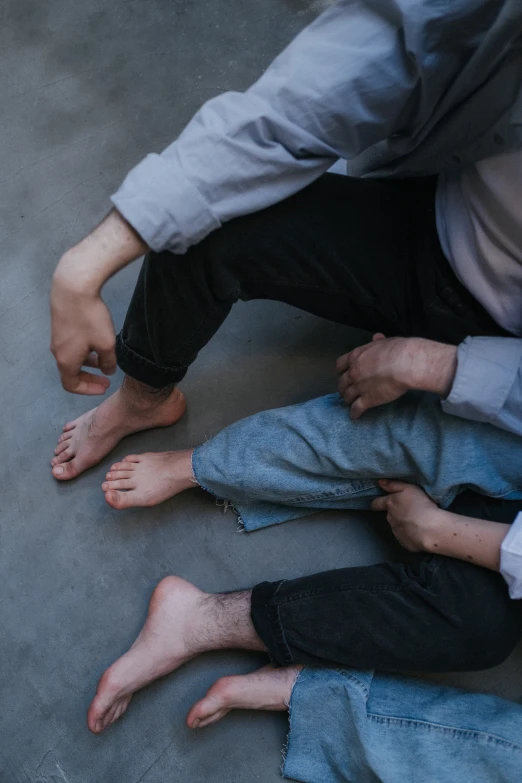 a group of people sitting on the ground next to each other, an album cover, by Elsa Bleda, unsplash, incoherents, father with child, exposed toes, two men hugging, possibly extra limbs