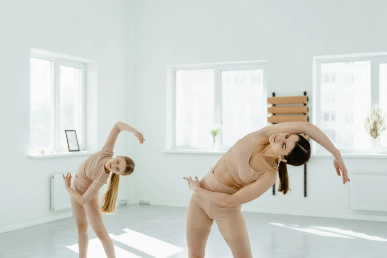 a couple of women standing next to each other in a room, pexels contest winner, arabesque, various bending poses, plain stretching into distance, profile image