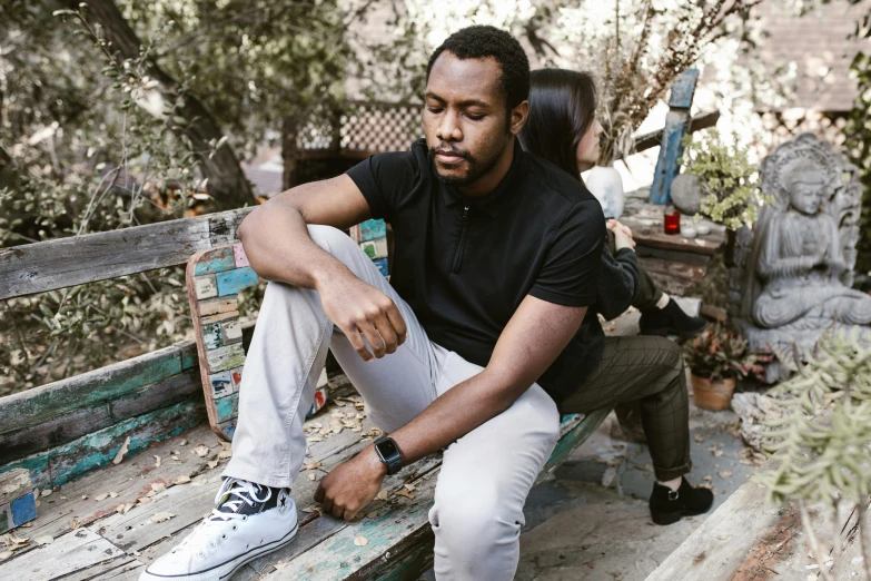 a man sitting on top of a wooden bench, an album cover, pexels contest winner, : kendrick lamar, miranda meeks, serious expression, wearing pants and a t-shirt