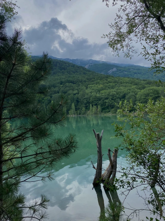 a lake surrounded by trees with a mountain in the background, st cirq lapopie, low quality photo, spooky photo, 8k))