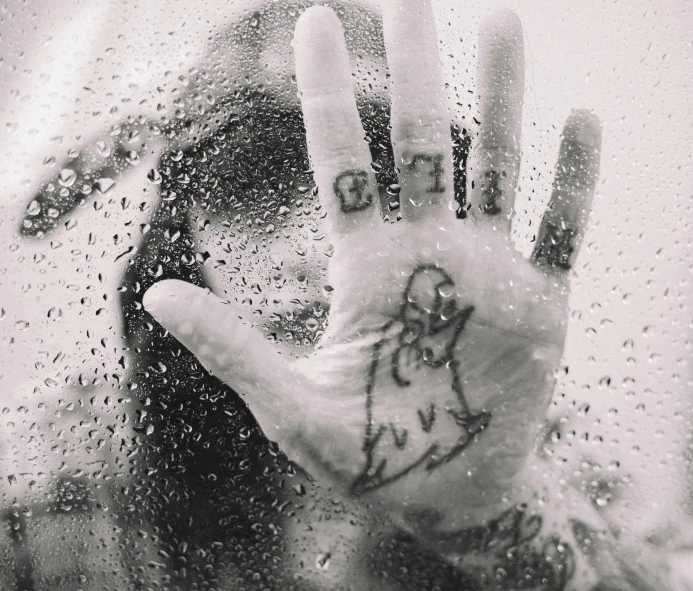 a person holding their hand up in front of a window, a black and white photo, tumblr, graffiti, lsd water, tattoos, raining!, holding nevermore
